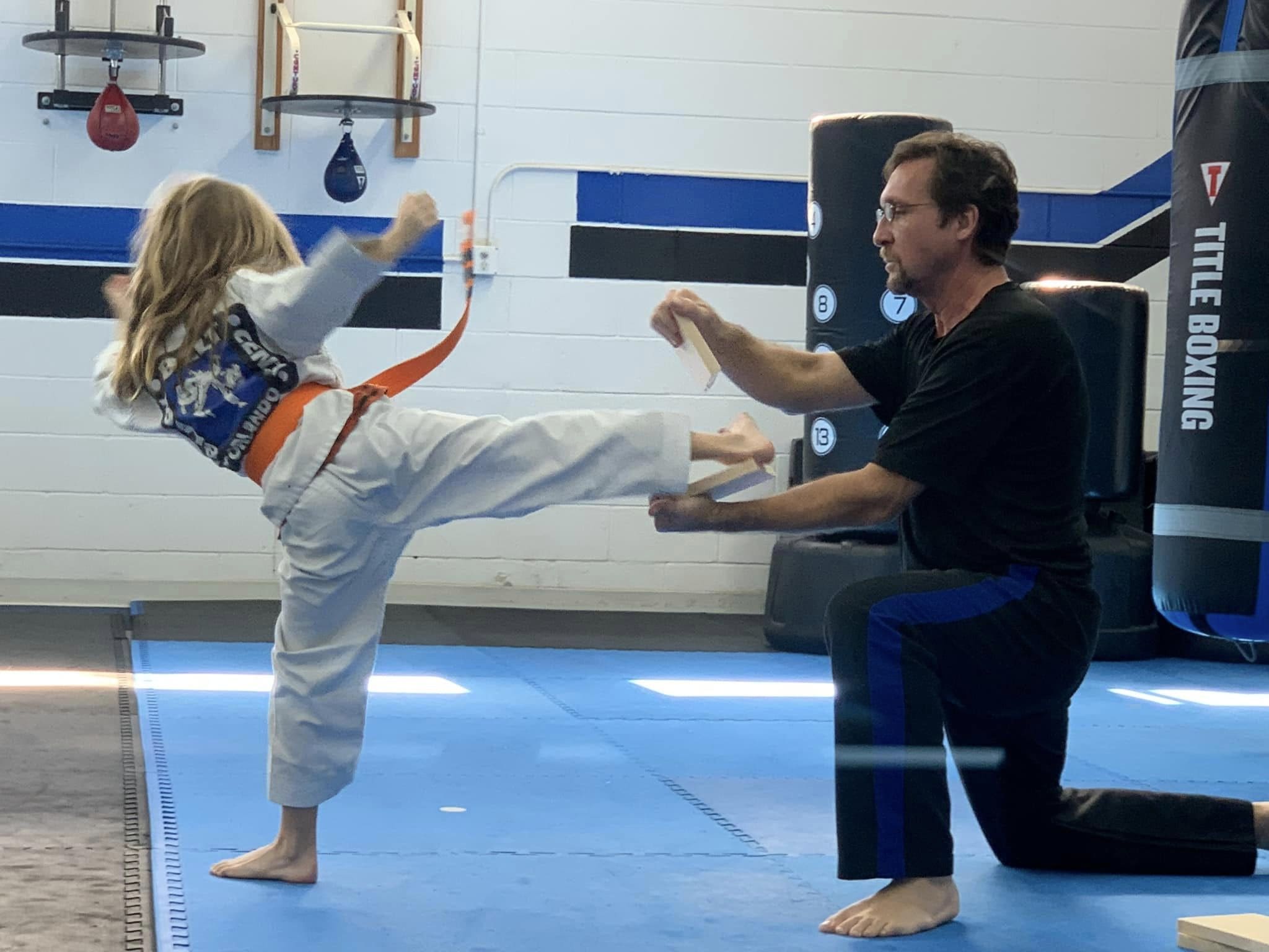 young girl karate kicking board